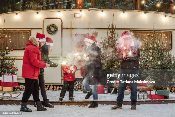 happy family have a good time together with sparklers near decorated motorhome in winter. christmas and new year concept. - year in focus trailer stock pictures, royalty-free photos & images