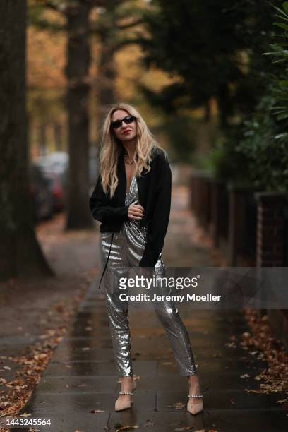 Sue Giers seen wearing SoSUE Blouson Shiny Black, silver Zara heels, Halston silver shiny jumpsuit, Vintage YSL black sunglasses on November 17, 2022...