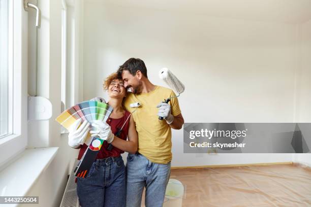 cheerful couple having fun during home renovation process. - holding paint roller stock pictures, royalty-free photos & images