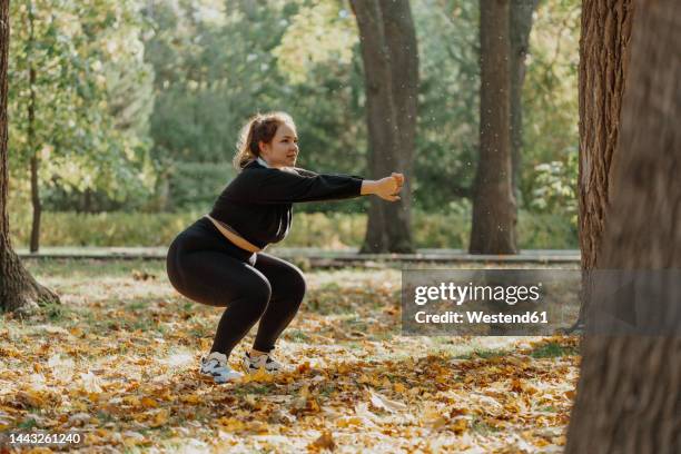 young woman squatting in park - entrenamiento-sin-material fotografías e imágenes de stock