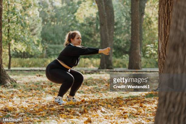 young woman squatting in park - bodyweight training stock pictures, royalty-free photos & images