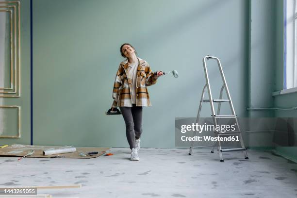 happy young woman walking with work tools in apartment - step stool stock pictures, royalty-free photos & images