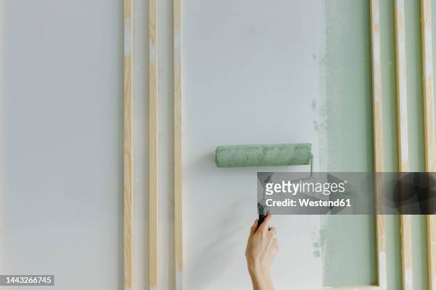 hand of woman painting with paint roller on wall at home - a woman with paint stock-fotos und bilder