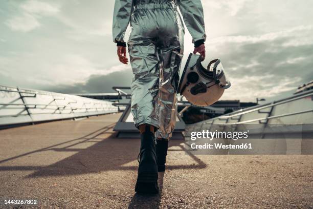 hand of astronaut holding space helmet walking on footpath - astronaut hand stock pictures, royalty-free photos & images