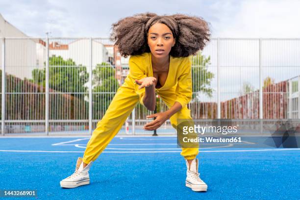 young woman gesturing and dancing on basketball court - woman yellow basketball stock pictures, royalty-free photos & images