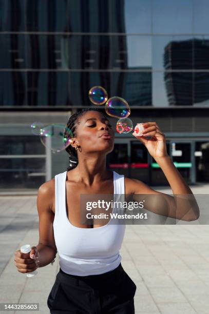 happy woman blowing bubbles enjoying on footpath - bubbles happy stockfoto's en -beelden