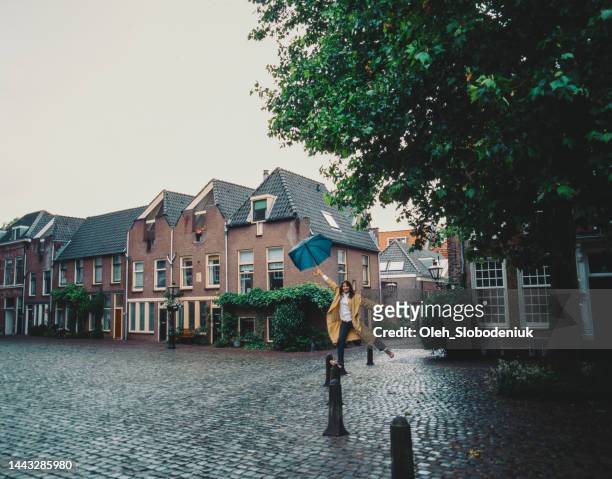 woman walking under the rain in leiden - south holland stock pictures, royalty-free photos & images