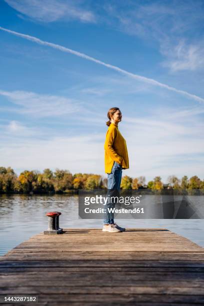 woman standing on jetty under sky - man side standing stock-fotos und bilder