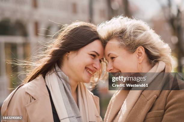 happy mother and daughter touching foreheads - オーバーコート ストックフォトと画像