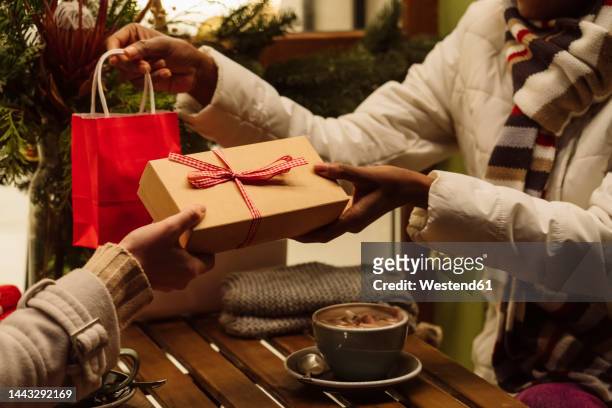 women exchanging gifts with each other on christmas - giving gifts stock pictures, royalty-free photos & images