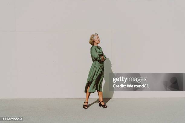 thoughtful woman with arms crossed in front of white wall - 50 54 ans photos et images de collection
