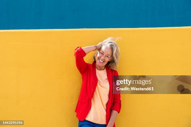 happy woman with hand in hair wearing red blazer - rode blazer stockfoto's en -beelden