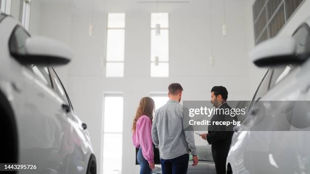 car salesman showing new cars to couple - car show room stock pictures, royalty-free photos & images