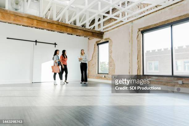 female real estate agent shows businesswomen open loft for office - commercial real estate agent stock pictures, royalty-free photos & images