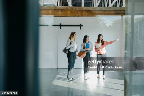 two businesswomen looking for office space listen to real estate agent - commercieel vastgoed stockfoto's en -beelden