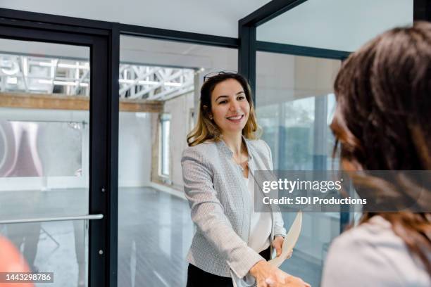 female real estate agent at the rental property greets unrecognizable client - commercieel vastgoed stockfoto's en -beelden