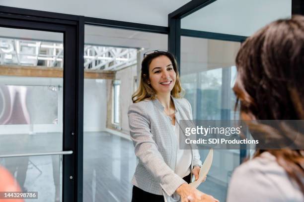 female real estate agent at the rental property greets unrecognizable client - commercial property imagens e fotografias de stock