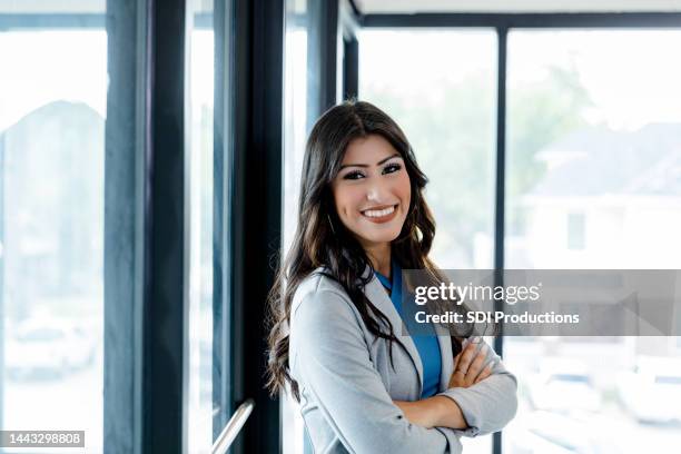 successful female bank manager poses for headshot with arms crossed - banker portrait imagens e fotografias de stock