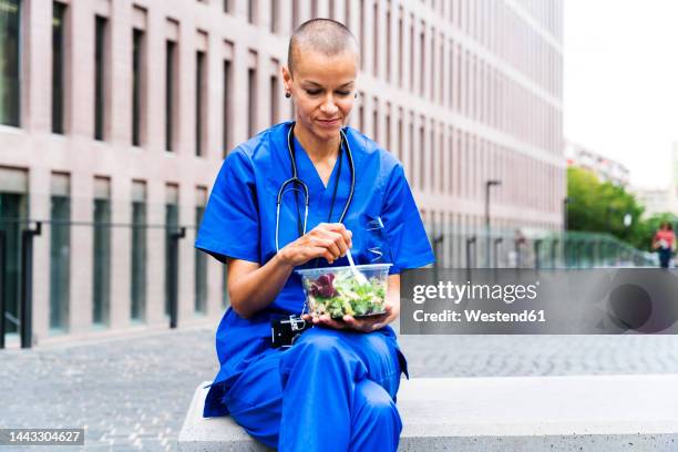 female nurse having salad on bench - doctor lunch break stock pictures, royalty-free photos & images