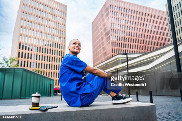 smiling nurse day dreaming on bench in city - pensive bildbanksfoton och bilder