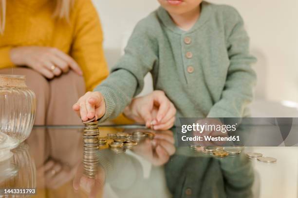 mother with son counting coins on table at home - poland money stock pictures, royalty-free photos & images