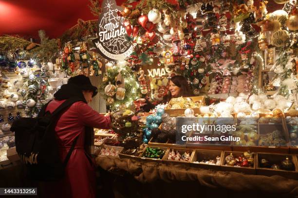 Visitor makes a purchase at a stall selling glitzy Christmas tree decorations on the first day of the Christmas market at Bebelplatz square on...