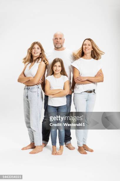 smiling woman and daughters with arms crossed by man in studio - couple jeans shirt stock-fotos und bilder