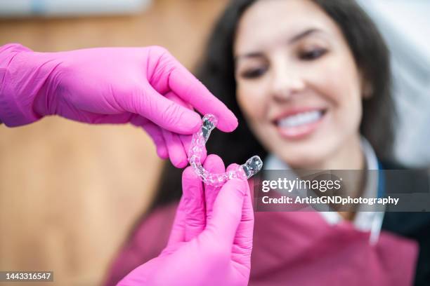 happy patient looking at dental aligners. - adult braces stock pictures, royalty-free photos & images