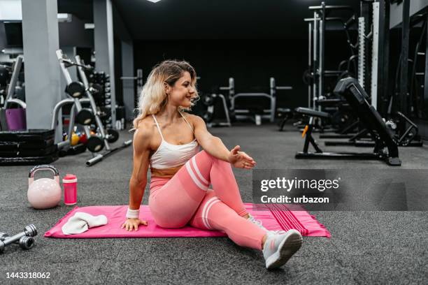 young muscular woman stretching before working out at the gym - tough decisions stock pictures, royalty-free photos & images