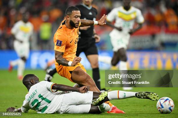 Memphis Depay of Netherlands is challenged by Youssouf Sabaly of Senegal during the FIFA World Cup Qatar 2022 Group A match between Senegal and...