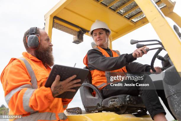 female fork lift driver talking with a male co-worker - ware house worker forklift stock pictures, royalty-free photos & images