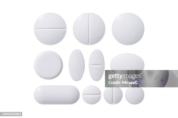 white pills of various shapes isolated on white - pills fotografías e imágenes de stock