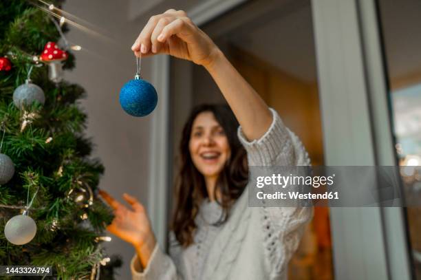 woman holding christmas ornaments to decorate christmas tree - decorare l'albero di natale foto e immagini stock