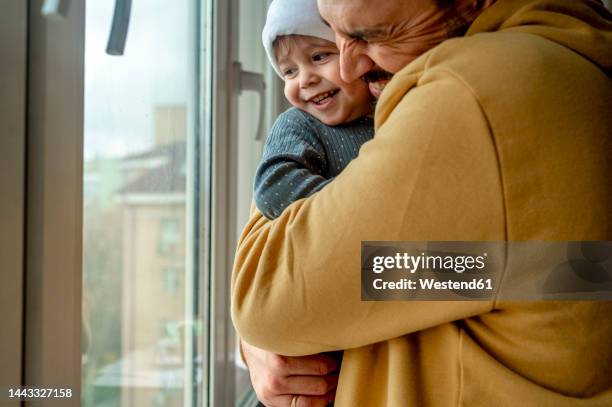 father and son hugging each other at home - baby father hug side stock-fotos und bilder