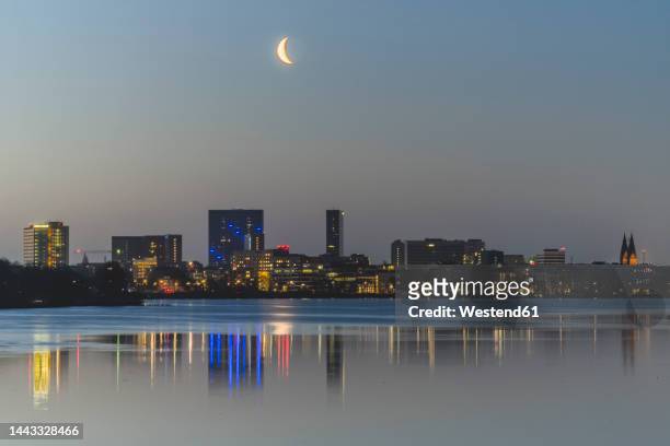 germany, hamburg, moon rises over outer alster lake with city skyline in background - alster lake stock pictures, royalty-free photos & images