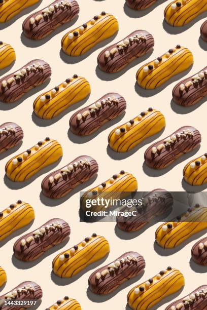 chocolate eclairs repetition pattern on beige - eclairs stock pictures, royalty-free photos & images