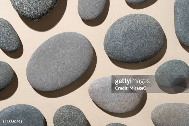 gray pebbles flat lay on beige background - pebbles stockfoto's en -beelden