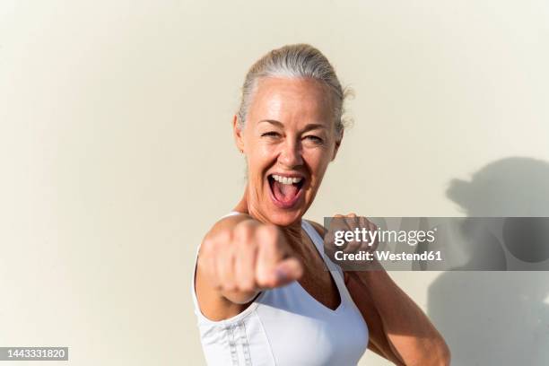 happy woman showing fists in front of wall on sunny day - body conscious bildbanksfoton och bilder