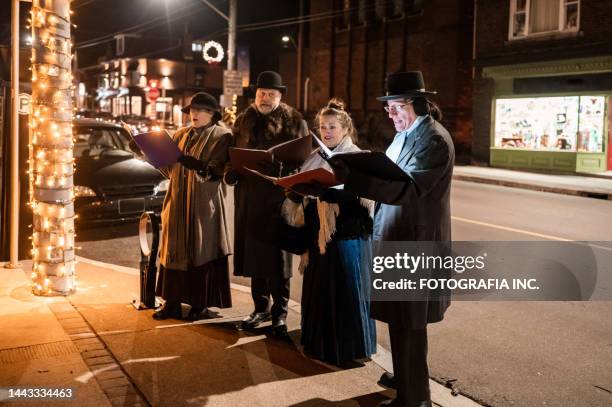 mature people singing christmas carols outdoors at night - carol singer stock pictures, royalty-free photos & images