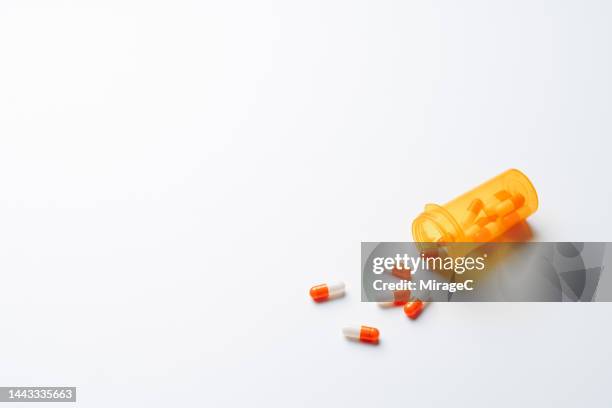 capsules spilled from a prescription medicine pill bottle - recipiente para las píldoras fotografías e imágenes de stock