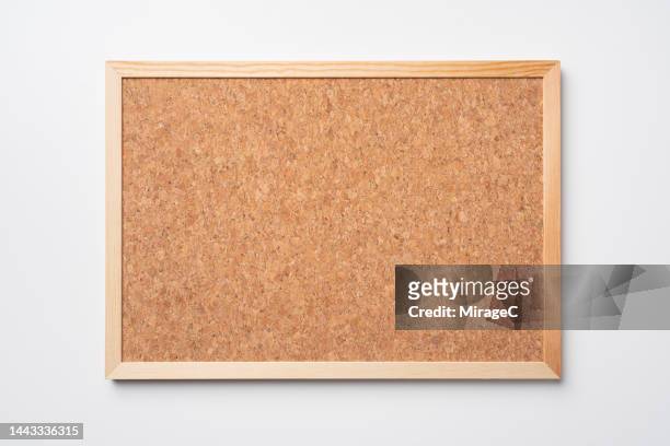 blank rough cork board hanging on white wall front view - tablón de anuncios fotografías e imágenes de stock