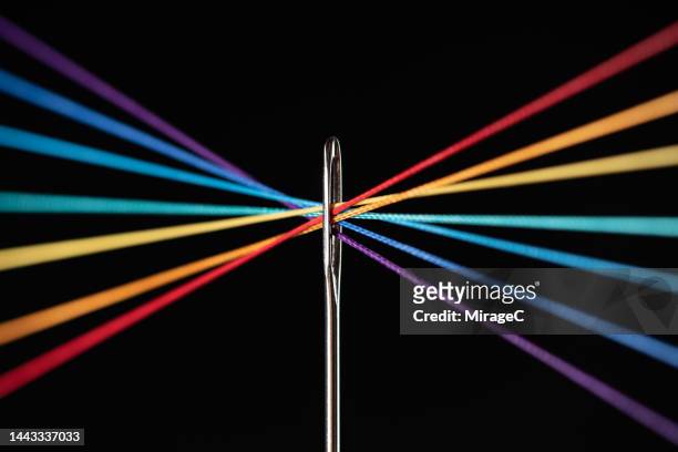 rainbow colored threads converge through needle eyelet - sewing needle stock pictures, royalty-free photos & images