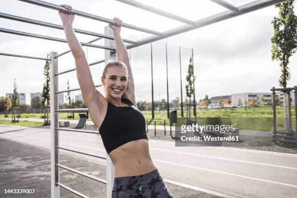 happy sportswoman exercising on horizontal bar - gymnastics equipment stock pictures, royalty-free photos & images