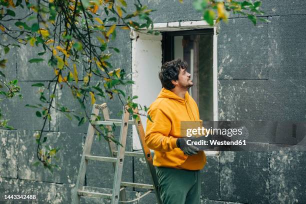 man holding polystyrene looking at wall of house - house insulation not posing stock pictures, royalty-free photos & images