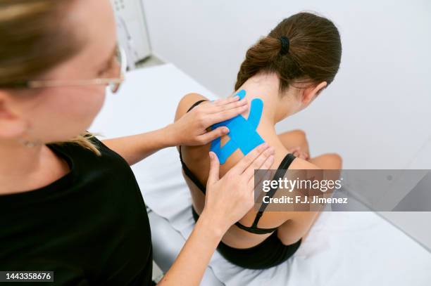 chiropractor placing elastic theurapetic tape on patient's neck - kinesiotape stock-fotos und bilder