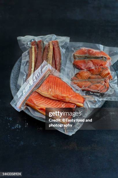 vacuum packed different pieces of salmon on a dark blue background - vacuum packed stock pictures, royalty-free photos & images