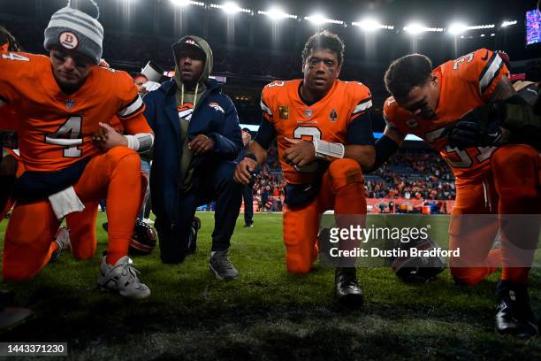 Quarterback Russell Wilson of the Denver Broncos kneels with teammates in prayer after a game against the Las Vegas Raiders at Empower Field at Mile...
