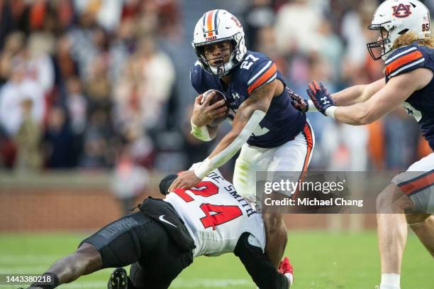 Running back Jarquez Hunter of the Auburn Tigers looks to escape a tackle by linebacker Derrick Smith of the Western Kentucky Hilltoppers at...