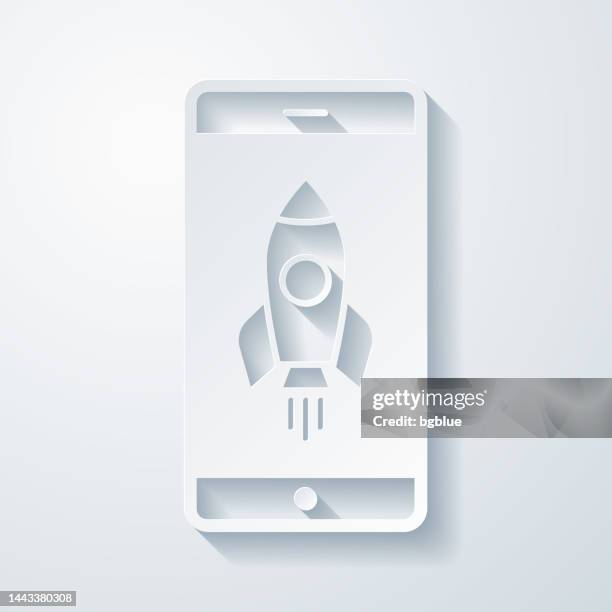 smartphone with rocket. icon with paper cut effect on blank background - paper rocket launch stock illustrations