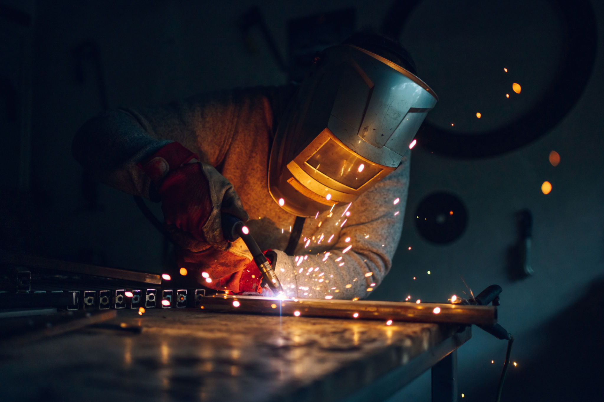 Man worker welding metal with welding machine in a factory or workshop Man worker welding metal with welding machine in a factory or workshop